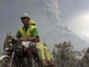 Villagers ride on a motorcycle as Mount Merapi continues to erupt.