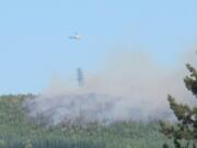 A helicopter makes a water drop on a wildfire burning Friday evening near the East Fork Lewis River near the mouth of Dole Valley in northeast Clark County.