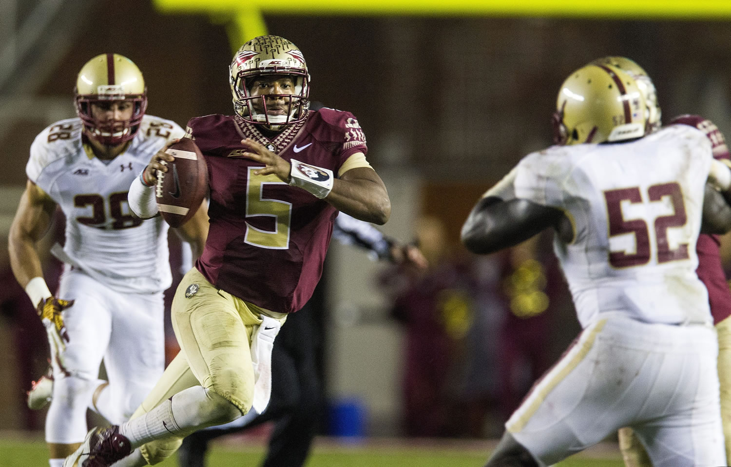 Florida State quarterback Jameis Winston, center, scrambles past Boston College defenders Matt Milano, left, and Steven Daniels in the second half of an NCAA college football game in Tallahassee, Fla., Saturday, Nov. 22, 2014. Florida State defeated Boston College 20-17.