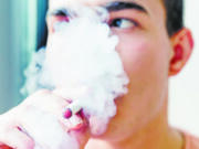 A young man uses an e-cigarette.