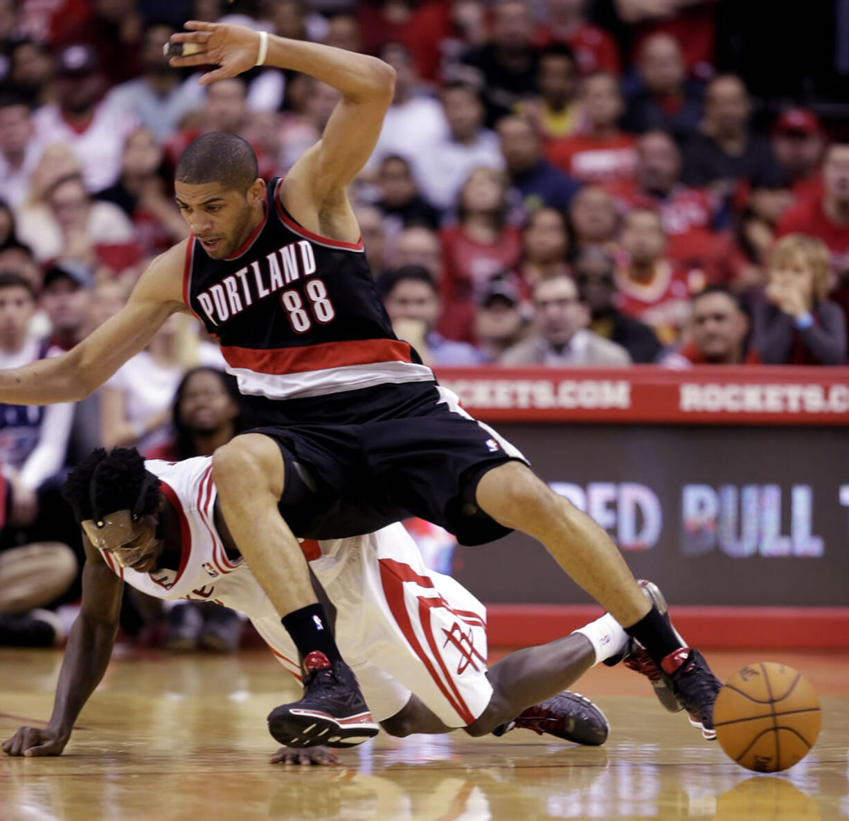 Portland Trail Blazers' Nicolas Batum (88) falls on Houston Rockets' Patrick Beverley (2) while chasing a loose ball during the fourth quarter of an NBA basketball game Sunday, March 9, 2014, in Houston. The Rockets won in overtime 118-113. (AP Photo/David J.