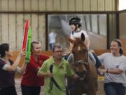 Jonathan Lopez, 7, who has cerebral palsy, watches therapist Kristi Immitt, far left, while volunteers guide Patron during the boy's hippotherapy session at Equest on March 31.