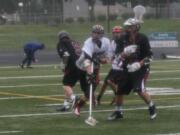 Zach Quist slings the ball away from two Eastlake lacrosse players, at Doc Harris Stadium.