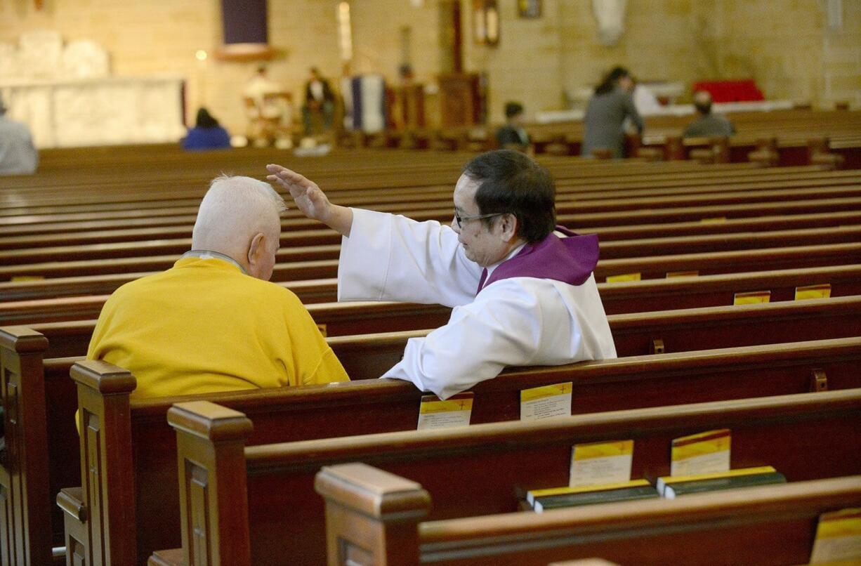 The Rev. Arcadio Munoz gives absolution to a parishioner at St. Mary's Church in Dumont, N.J.