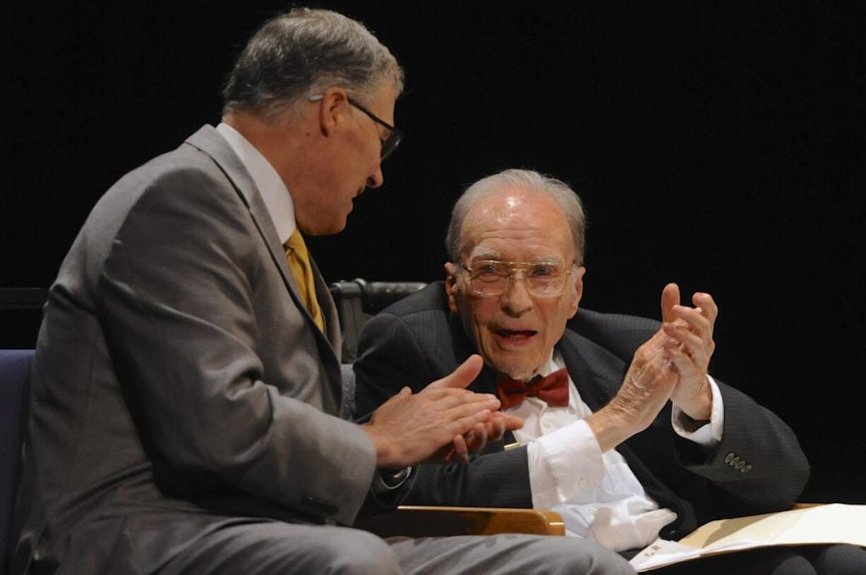 Washington Gov. Jay Inslee, left, and Dan Ogden applaud a speaker during a memorial service for Val Ogden on April 26, 2014, at Clark College. Dan Ogden died Wednesday.