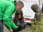 Grandfather and granddaughter, Randy Curtis and Olivia Brotherton, help remove the plastic from the newly refurbished reading girl statue. They spearheaded efforts to replace the statue's book, which was stolen more than a decade ago.