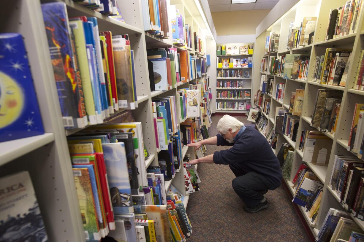 Librarian Sean McGill looks for a title at the Ridgefield library in March.