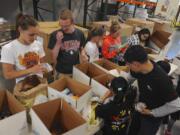 Volunteers, from left, Ellery Roberts, Michael Hall, Jennifer Ross, Megan Wilson and Esther Pisano sort food donations at a regular Tuesday night repack event at the Clark County Food Bank.