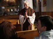 Bishop Karl Rodig speaks to Elizabeth Shanaver, left, and her partner, Melissa McDaniel, at St. Anthony Church in Detroit.