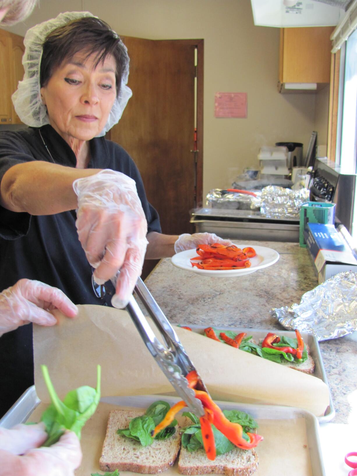 Alla Fleischer prepared sandwiches with lemon chicken and roasted red peppers, with assistance from volunteer Lynne Foster, Friday at the Camas Community Center. Fleischer, kitchen coordinator for The Meals on Wheels People Camas-Washougal, will retire at the end of this week.