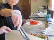 Alla Fleischer prepared sandwiches with lemon chicken and roasted red peppers, with assistance from volunteer Lynne Foster, Friday at the Camas Community Center. Fleischer, kitchen coordinator for The Meals on Wheels People Camas-Washougal, will retire at the end of this week.