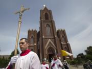 An altar server emerges, carrying a cross, from the Proto-Cathedral of St. James the Greater on Sunday.