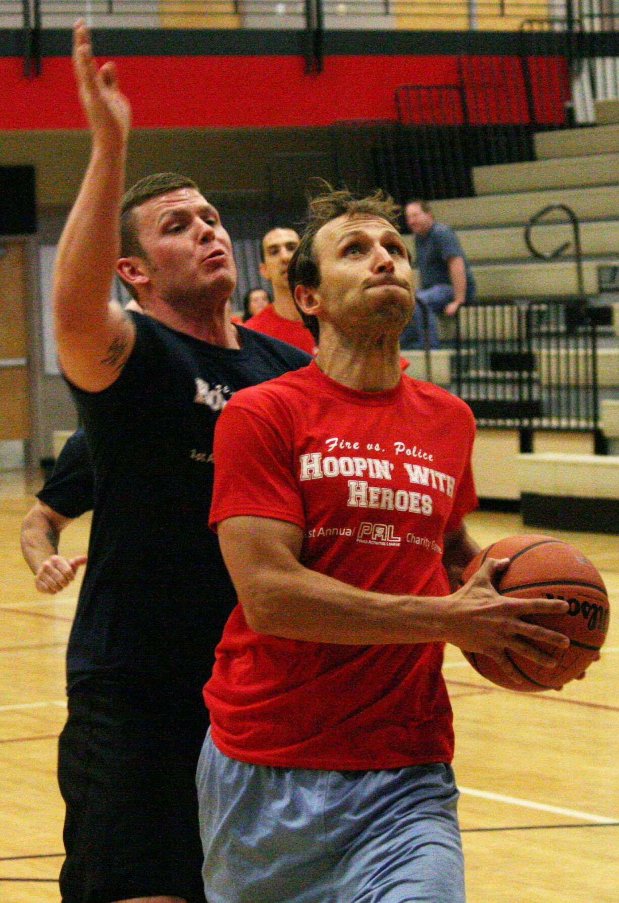 Firefighter Matt Baldwin gets by police officer Colton Price on a fast break during the Camas-Washougal Fire vs. Police charity basketball game.