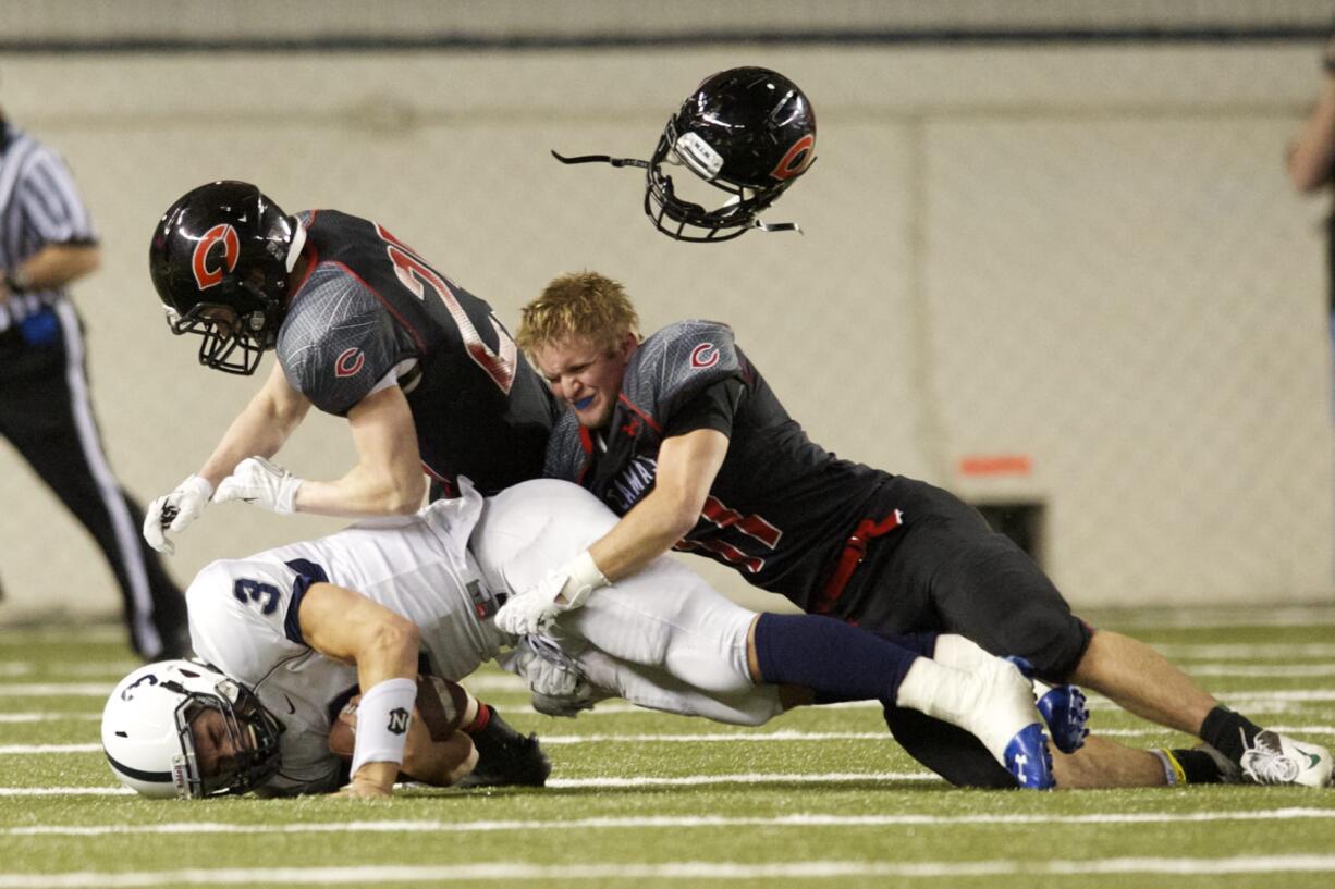 Camas defenders Adam Dawson, right, and Cole Zarcone take down Chiawana ball carrier Joey Zamora.