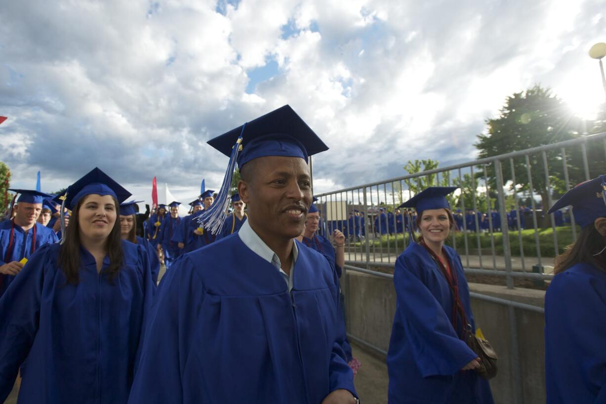 Turi Sado, 38, walks into the Sleep County Amphitheater with other Clark College graduates Thursday. Sado said he experienced a powerful moment in a Kenyan refugee camp seven years ago when he saw many people dying.