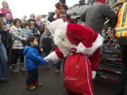 Santa greets Sage Zhuang after arriving on the SP&amp;S 700 steam locomotive.