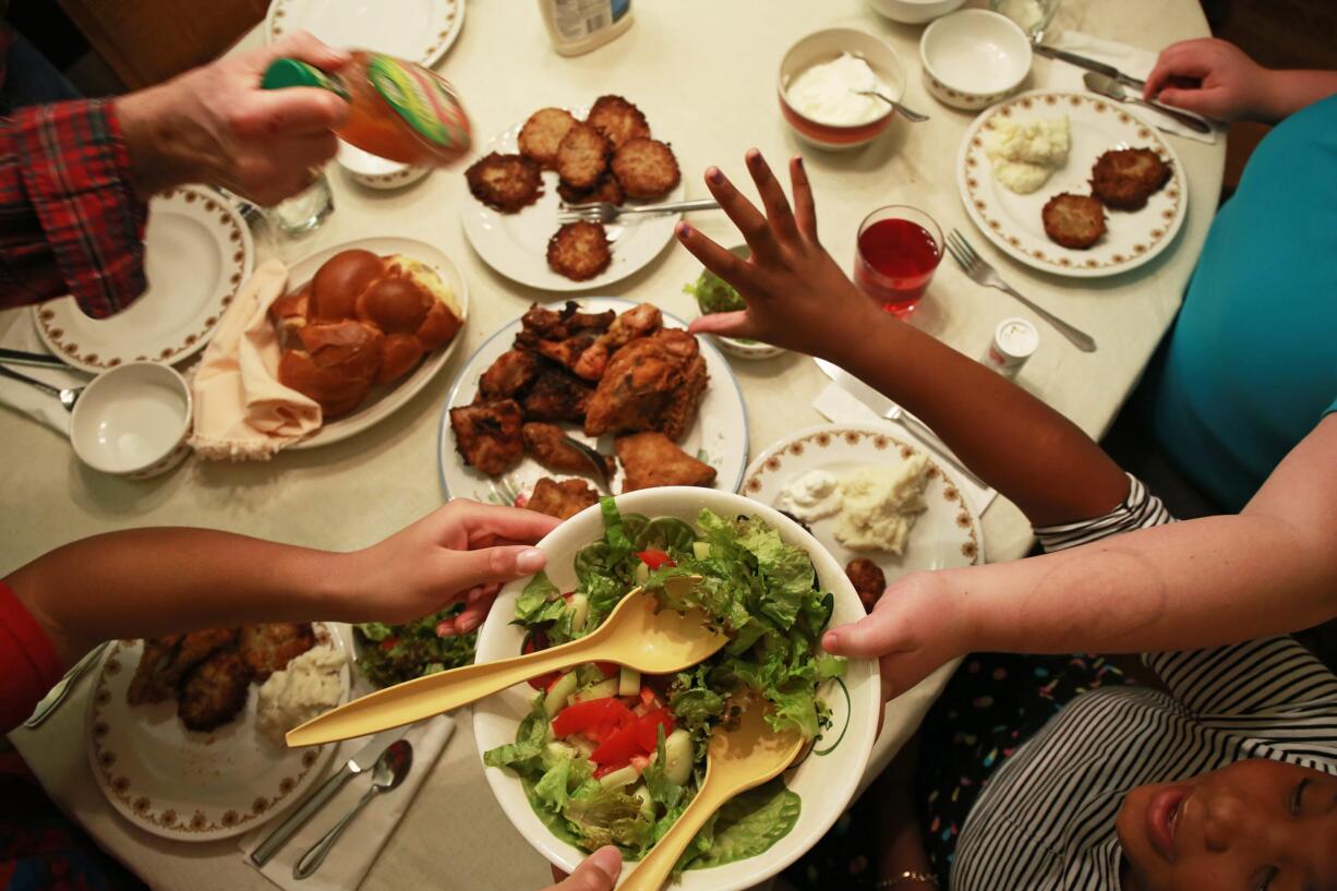 Meira Burnett, 11, lower right, reaches for salad dressing during a Sabbath dinner with her family Dec.