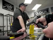 Brightwater Ventures Firearm Sales owner Nick Pratka waits as a customer looks at handguns.