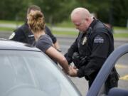 Ridgefield police Officer Jason Ferriss detains a woman after a traffic stop earlier this month on Pioneer Street, east of downtown.