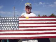 Army veteran Philip Johnson sells an American flag wall hanging he made from reclaimed cedar at a flea market to raise funds to build a veterans memorial in Battle Ground.