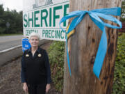 Theresa Miller of the Clark County Sheriff&#039;s Office Central Precinct stands next to a blue ribbon tied to a pole in Brush Prairie on Friday. Community members have recently shown an outpouring of support for law enforcement, including cards, cake and by decorating offices with blue ribbons.