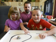 Siblings Hailey and Parker King play with Ringo, a robotic toy they helped design with their dad, Kevin King, center, on Thursday. Kevin King recently raised more than $80,000 on Kickstarter to start manufacturing and selling the robotic toys out of their Vancouver workshop.