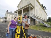 Graduate student Emily Taber and Doug Wilson, National Park Service archaeologist, use surveying equipment to set up a dig at the site of the 1854 Army flagstaff at Vancouver Barracks.