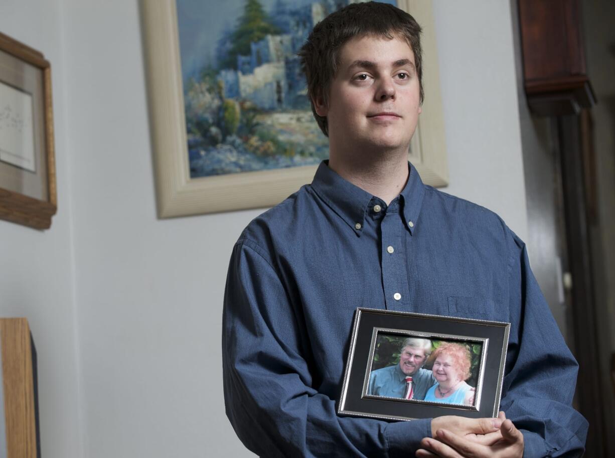 Jesse Rainey, holding a portrait of his parents Stan and Brenda Rainey, graduates from community college Friday.