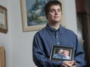 Jesse Rainey, holding a portrait of his parents Stan and Brenda Rainey, graduates from community college Friday.