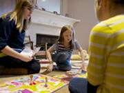 Kelly Slauson, 20, plays a game with Greta Brown, center, a child she cares for in Camas.