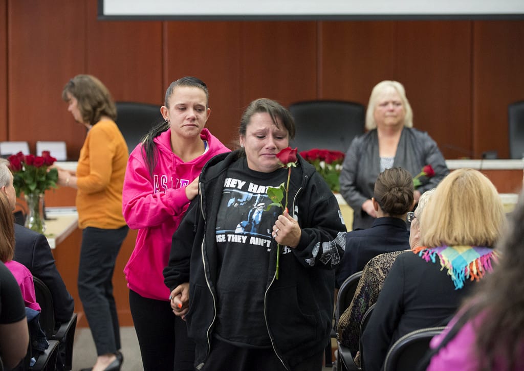 Amber Blanchard of Vancouver, center, fights back tears as she collects a rose in honor of the memory of her brother, Sloan Blanchard, while joined by her daughter, Manasseh Blanchard, in pink, Wednesday morning, Sept. 16, 2015 at the Vancouver Clark County Public Service Center. Family, friends, law enforcement officers, elected officials and others gathered to remember those the community has lost during National Day of Remembrance For Homicide Victims.