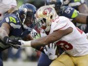 Seattle Seahawks' Bobby Wagner, left, closes in on San Francisco 49ers' Carlos Hyde, right, in the second half Sunday, Dec. 14, 2014, in Seattle.