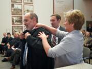 Rich Melnick gets help with his robe on Wednesday from his wife, Lori, and son, Ben, after he was ceremonially sworn in as a judge of the Washington state Court of Appeals Division 2.