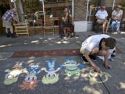 Jay Morton, 26, draws characters on the sidewalk on Main Street during the fourth annual Chalk the Walks in Uptown Village on Tuesday. His message?