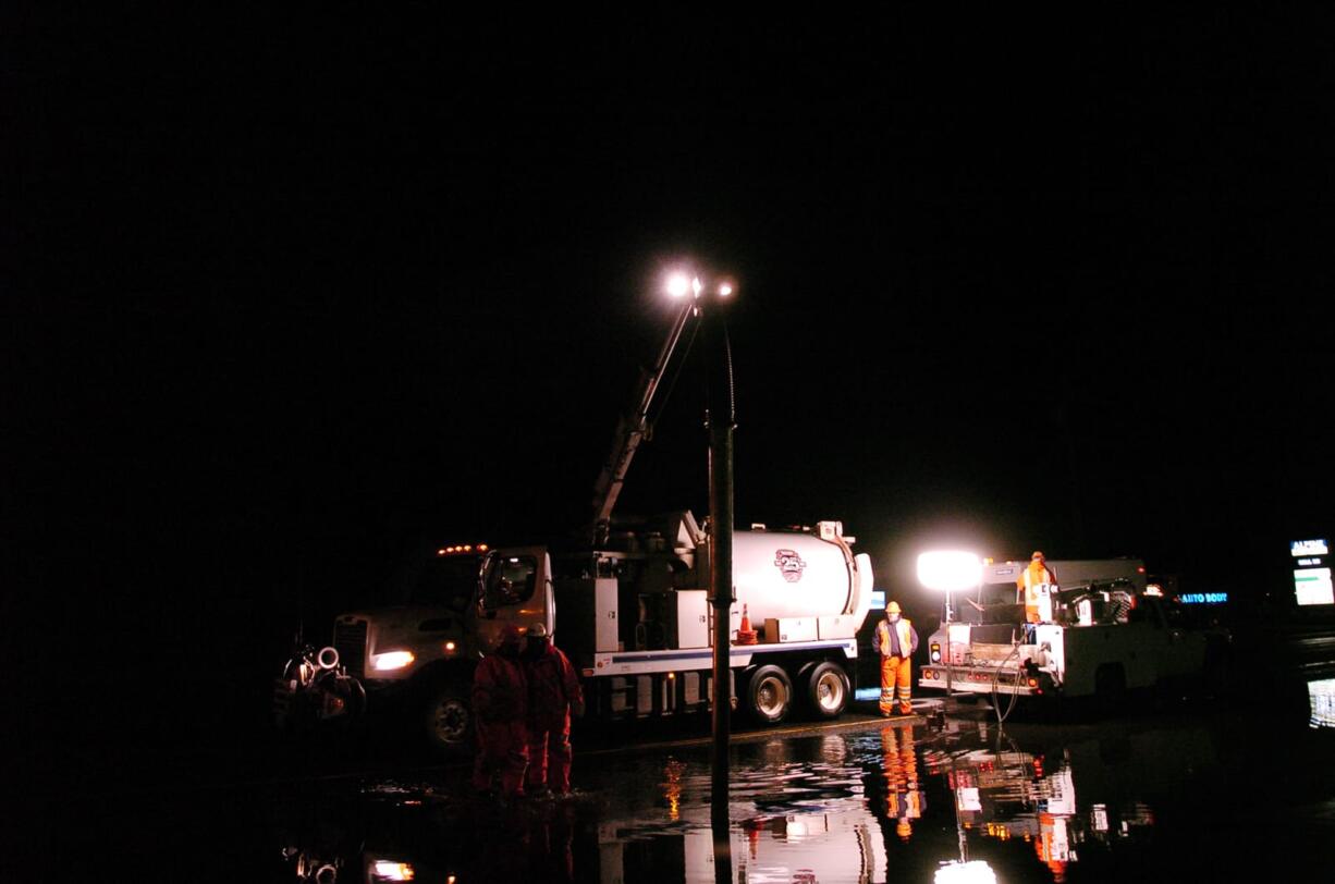 Crews vacuum up water off Northeast Fourth Plain Road on Tuesday evening, after a vehicle struck a fire hydrant, causing water to flood the roadway.