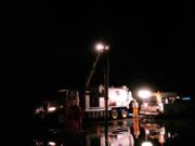 Crews vacuum up water off Northeast Fourth Plain Road on Tuesday evening, after a vehicle struck a fire hydrant, causing water to flood the roadway.