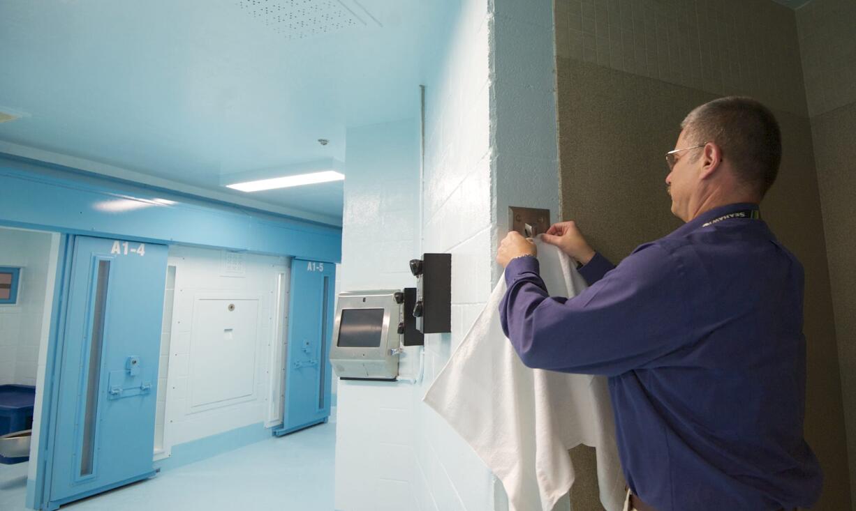 Clark County Jail Chief Ric Bishop demonstrates how a ball bearing is used in lieu of a hook to hold a towel inside a refurbished anti-suicide wing. The new area, dubbed A Pod 1, is scheduled to open in less than a month. Top: Clark County Jail Commander Kimberly Beltran gives a tour of a cell, which includes a platform that will be used as a bed.