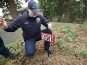 Fire District 6 Firefighter Chris Bottomley places a reflective address sign near a driveway in Hazel Dell.