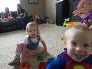 Ronda Jensen sits with her daughter Lilly, 9, as her 2-year-old twins, Gus and Eva, play on the living room in their Ridgefield home.