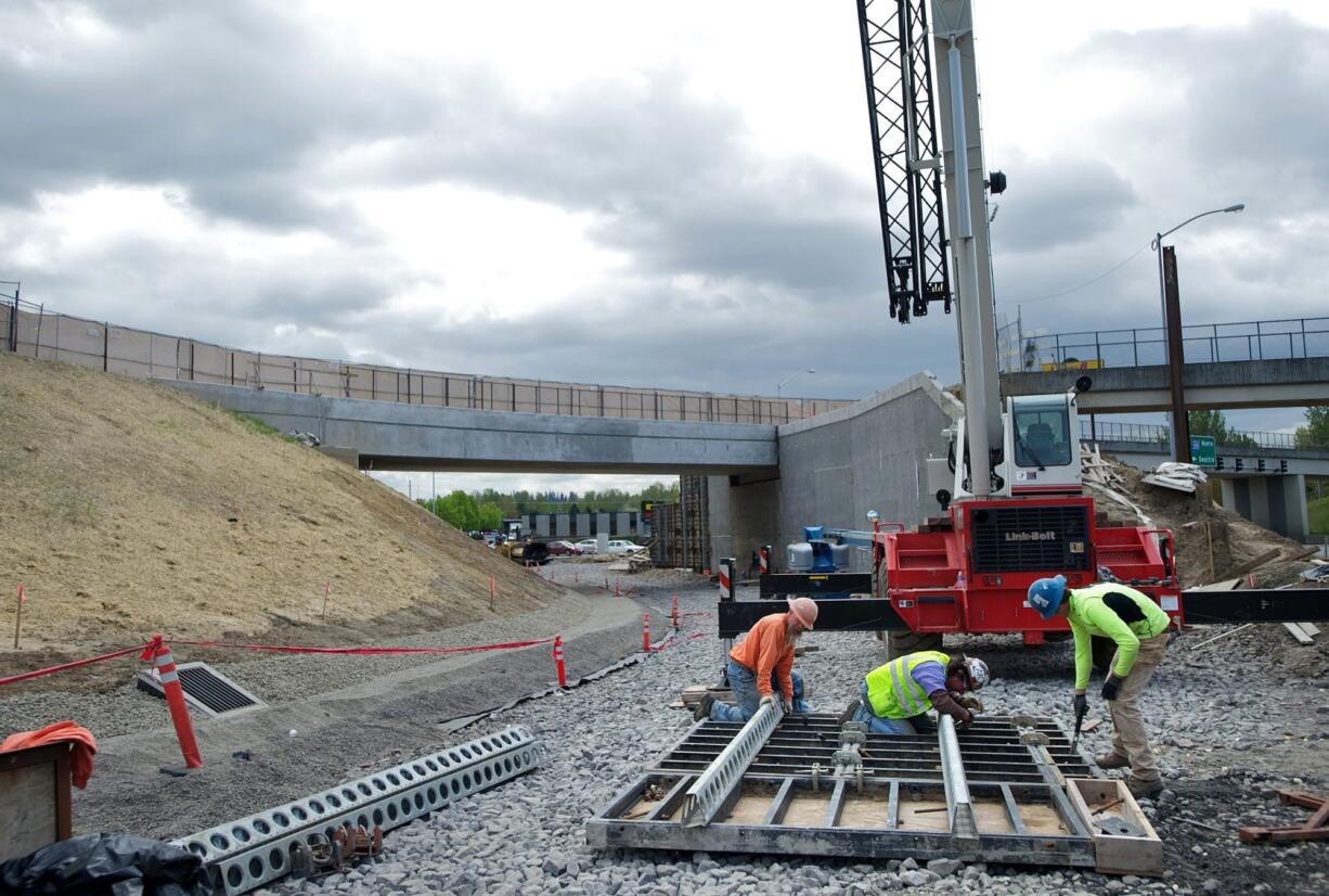 Workers disassemble a concrete form as the Oregon Department of Transportation continues work to expand the interchange at Interstate 205 and Northeast Airport Way in Portland.