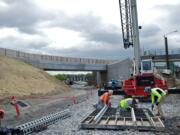 Workers disassemble a concrete form as the Oregon Department of Transportation continues work to expand the interchange at Interstate 205 and Northeast Airport Way in Portland.