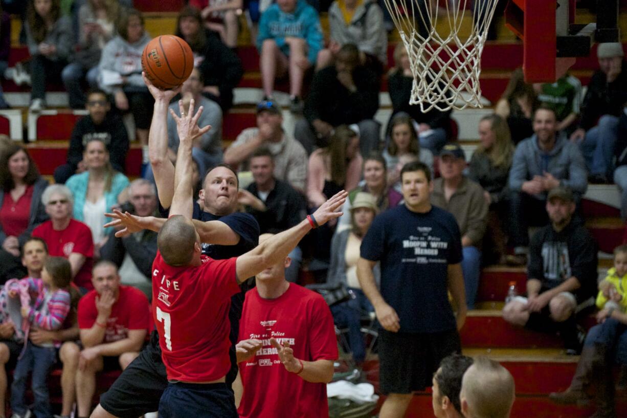 Steve Neal, from the Vancouver Police Department, puts up a hook shot over Vancouver Fire's John Larson in the first half of the Hoopin' with Heroes charity game Friday night at Fort Vancouver High School.