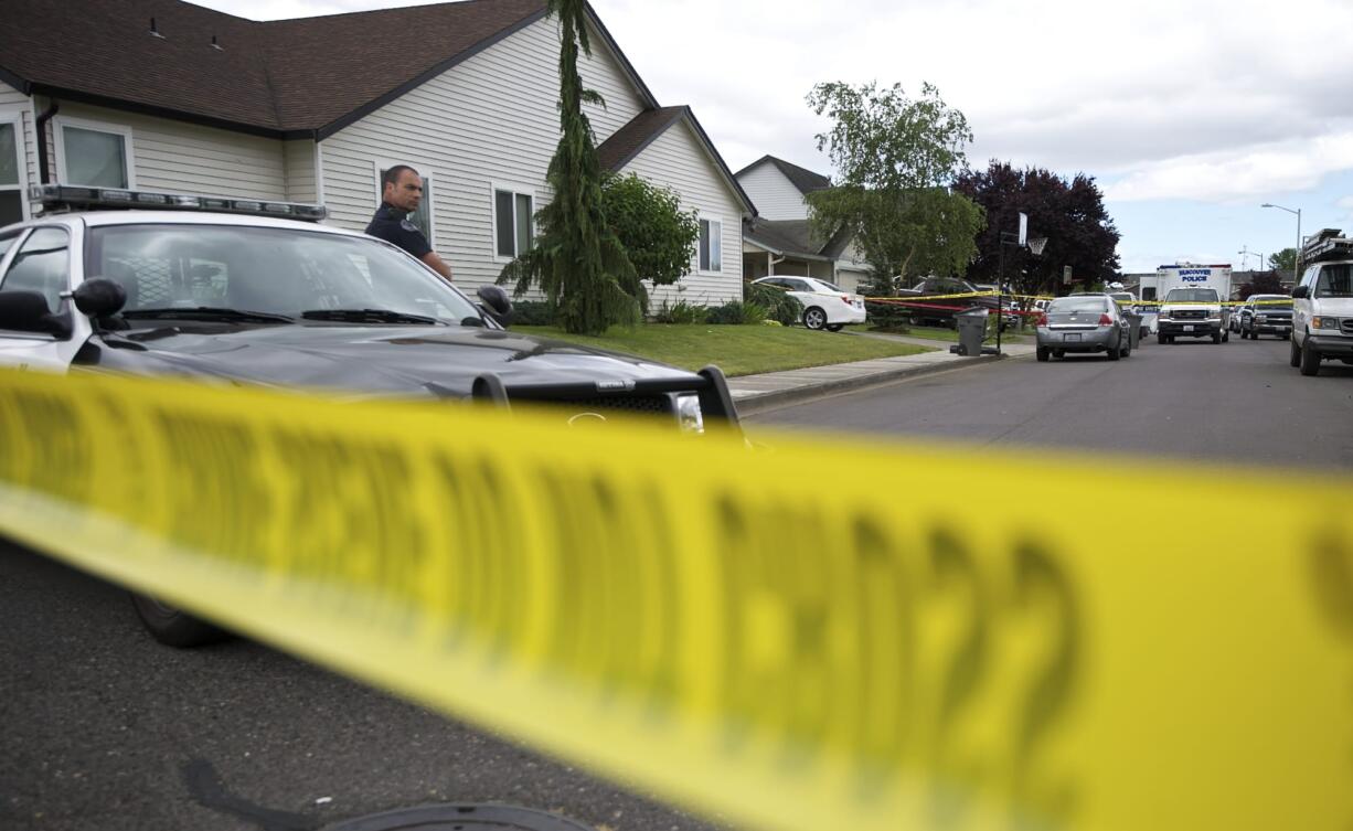 Vancouver Police officer Don Magarian watches the tape line as police investigate the scene of a shooting where two people were reported dead and a third injured in east Vancouver on Monday.