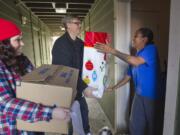 Volunteer Taylor Vossen, from left, and Woodland Rotary Club President Jeff Stay deliver a box of food to Latoya Black on Monday in Woodland.