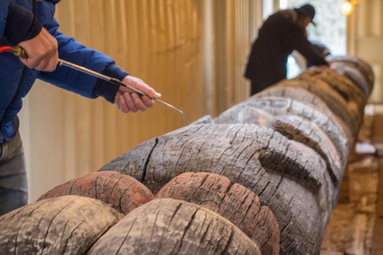 Volunteers work on the weathered Lelooska totem pole at the Oregon Zoo.