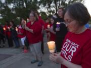 Gabby Sprenger, right, holds a candle as part of a Friday vigil at Clark College for 276 Nigerian girls who were kidnapped from school last month.