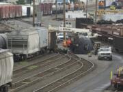 Crews work to flip a derailed tank car containing liquid asphalt in the BNSF Railway Vancouver yard near the Fourth Plain Boulevard overpass on Friday.