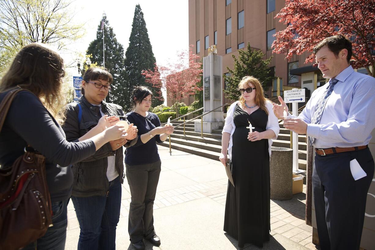 Ashley Myers of Portland, from left, Mitzy Timmins of Vancouver, Jessie Ghiglieri, a mental health outreach specialist with Americorps Vista; Brenda Huffstutler, a crime victim advocate with Lutheran Community Services Northwest; and Vancouver Mayor Tim Leavitt take part in a candlelight vigil Monday outside the Clark County Courthouse.