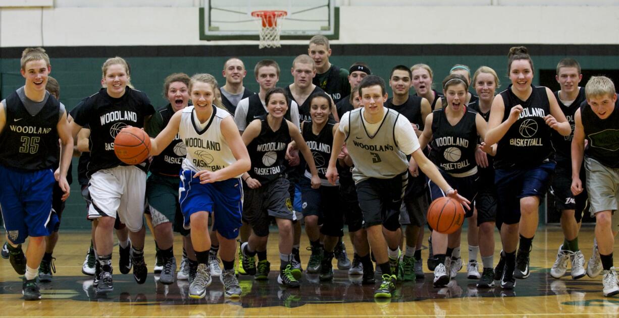 The Woodland boys and girls basketball teams, being led out by seniors Madison Sorensen and Tanner Huddleston (in light jerseys), are both one win from state in Yakima.