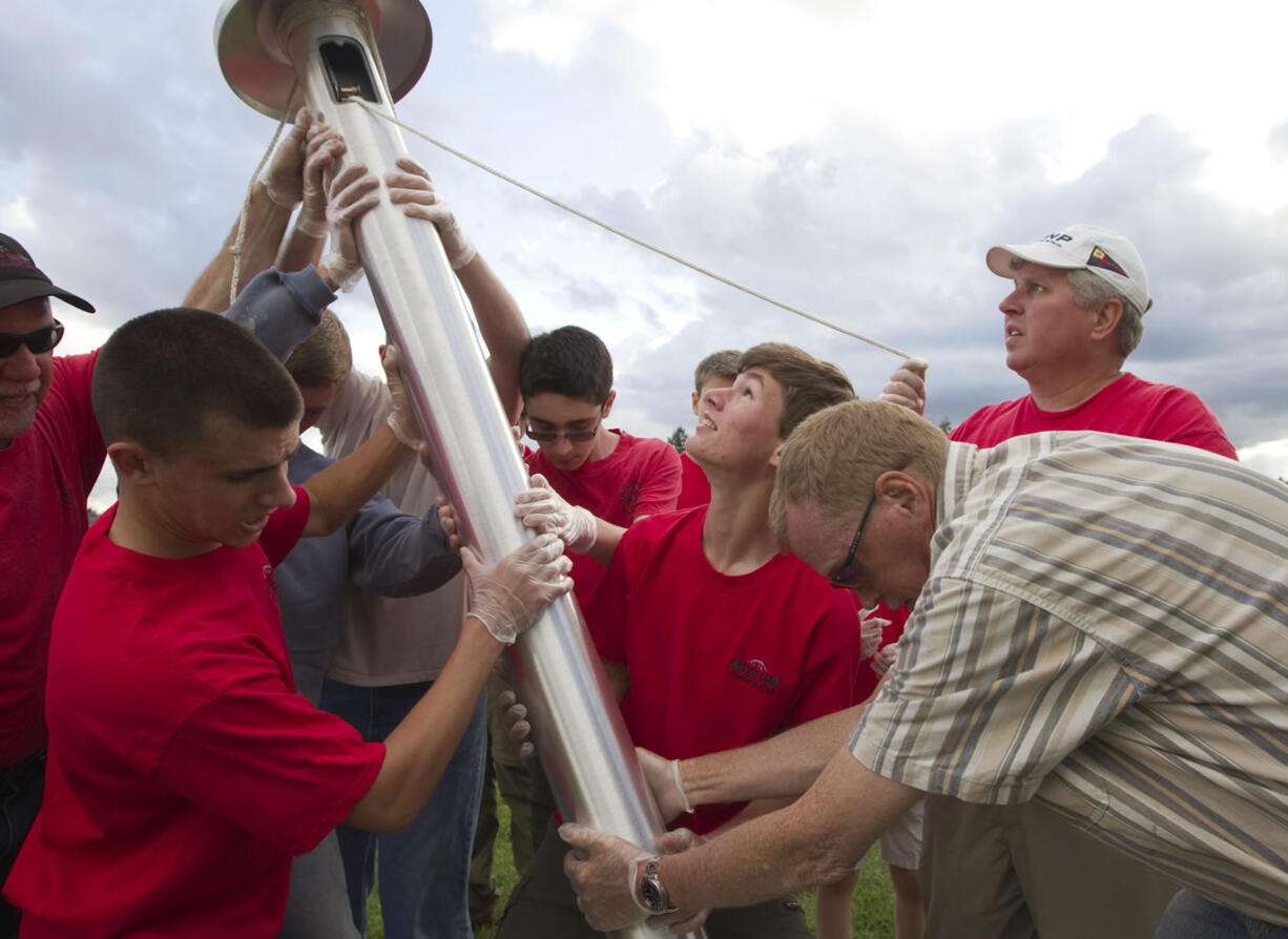 Connor Johnson, looking up at the pole, and a team of fellow Boy Scouts and adults put up a 30-foot flagpole Friday at the Harmony Sports Complex in Vancouver. Johnson organized the effort as his Eagle project to honor Capt. Christopher Stover, a U.S.